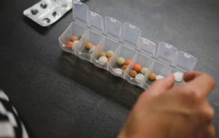 An open pill sorter shows an array of medications
