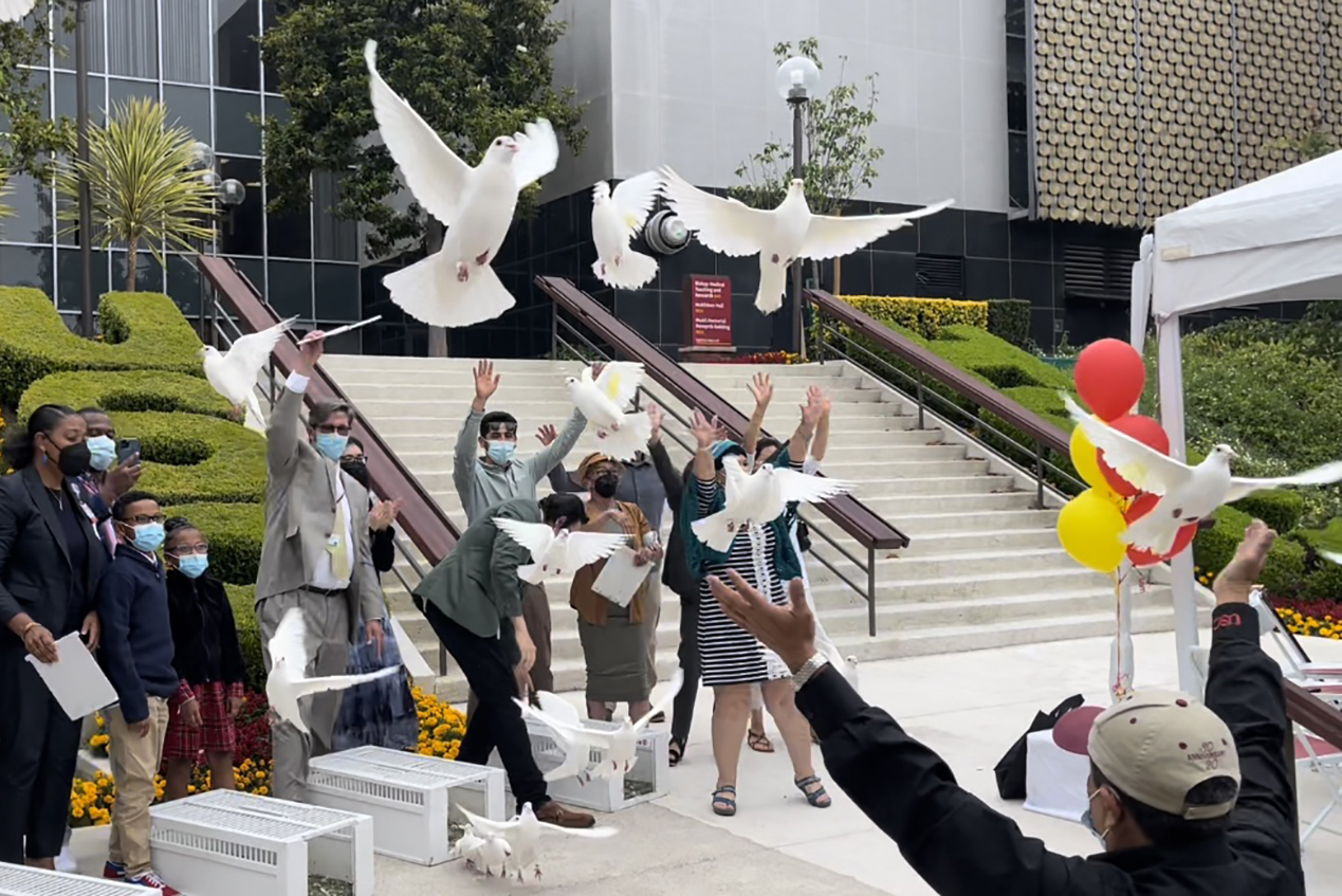 Roughly a half-dozen people release doves into the sky