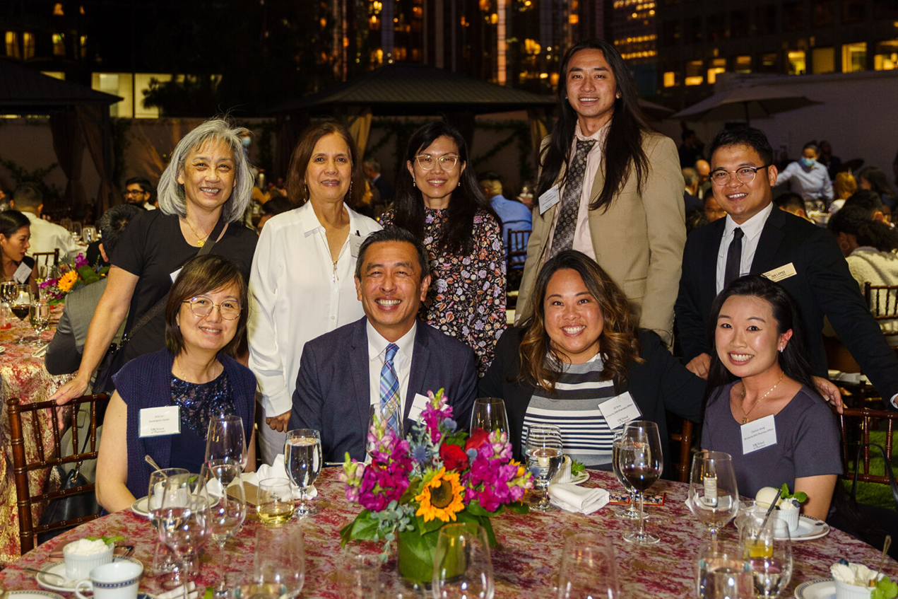 Nine people smile proudly at a reception dinner