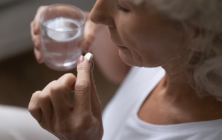 An older woman takes a pill.