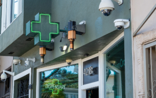 An illuminated green cross marks a dispensary storefront