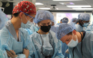 A surgeon bends over his work while two others look on