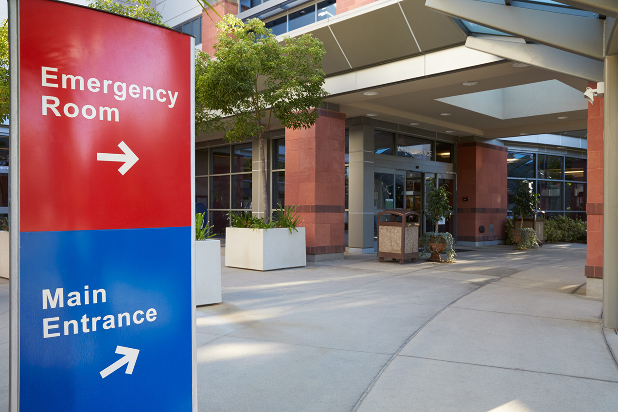 A red and blue sign points to an emergency room and main entrance