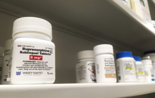 A pill bottle labeled, buprenorphine sits on a pharmacy shelf among other medications