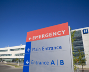 A sign outside a hospital points toward an emergency room entrance.