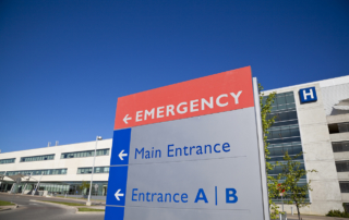 A sign outside a hospital points toward an emergency room entrance.