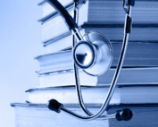 A stethoscope hangs over a stack of books