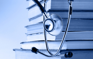 A stethoscope hangs over a stack of books
