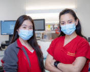 Two nurses in cardinal scrubs proudly smile for the camera