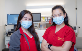 Two nurses in cardinal scrubs proudly smile for the camera