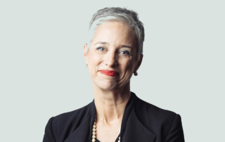 A professionally dressed woman with short, silver hair smiles warmly.