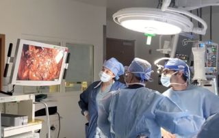 Urologic surgeons in scrubs examine a screen showing a patient's bladder