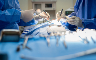 The hands of two surgeons perform a procedure on a patient's torso
