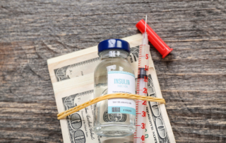 A rubber band secures insulin and a syringe to a bundle of cash
