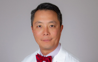 In a professional headshot, a doctor wears a bright red bowtie.