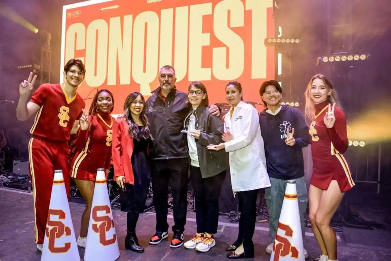 USC Spirit leaders (in uniforms, at far left and right) with presenters and recipients of the American Heart Association Heartsaver Hero Award (left-to-right), Stella Fogleman of the Los Angeles County Dept. of Public Health; Russ Romano; Sarah Van Orman; MD, Carolyn Kaloostian, MD, MPH, board member of the American Heart Association; student outreach ambassador for wellbeing and health, Kenneth Phung.
