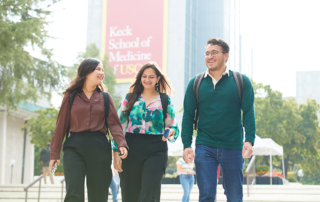 Three students happily walk through the Keck School of Medicine of USC campus.