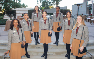 Seven young women stand gracefully and smile on a flight of steps outside USC Norris Cancer Hospital