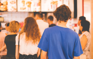 A teen boy waits in a long line at a fast food counter