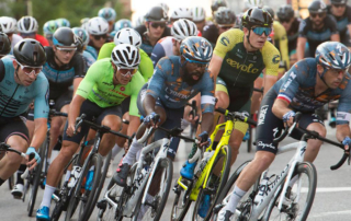 A tight crowd of cyclists rounds a turn in a race.
