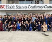 A large crowd poses for a photo outside the USC Health Sciences Conference Center