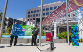 Two men present the Donate Life flag outside of Keck Hospital