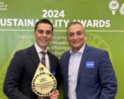 In front of a green banner that reads, Los Angeles Department of Water and Power 2024 Sustainability awards, Miguel Gonzalez holds up an award beside Erwin Morales.