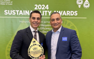 In front of a green banner that reads, Los Angeles Department of Water and Power 2024 Sustainability awards, Miguel Gonzalez holds up an award beside Erwin Morales.