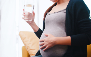 A pregnant woman drinks a glass of fluoridated tap water