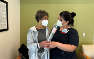 A Keck Medicine nurse gives a pink rose to an infusion center patient on Mother's Day
