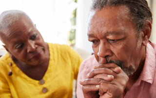 A woman comforts a man experiencing symptoms of dementia