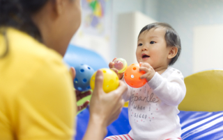 A woman plays with a baby to aid their development