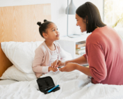 A mother performs a finger stick test on a small child with type 1 diabetes.