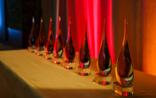 Several teardrop-shaped USC Mann Alumni Awards stand lined up on a table