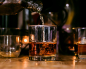 Several glasses of brown liquor on a table represent increased alcohol use.