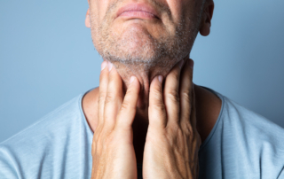 A man infected with HPV rubs his throat with a pained expression