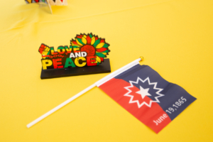 A miniature Juneteenth flag rests on a table beside a standup centerpiece reading, Love and Peace